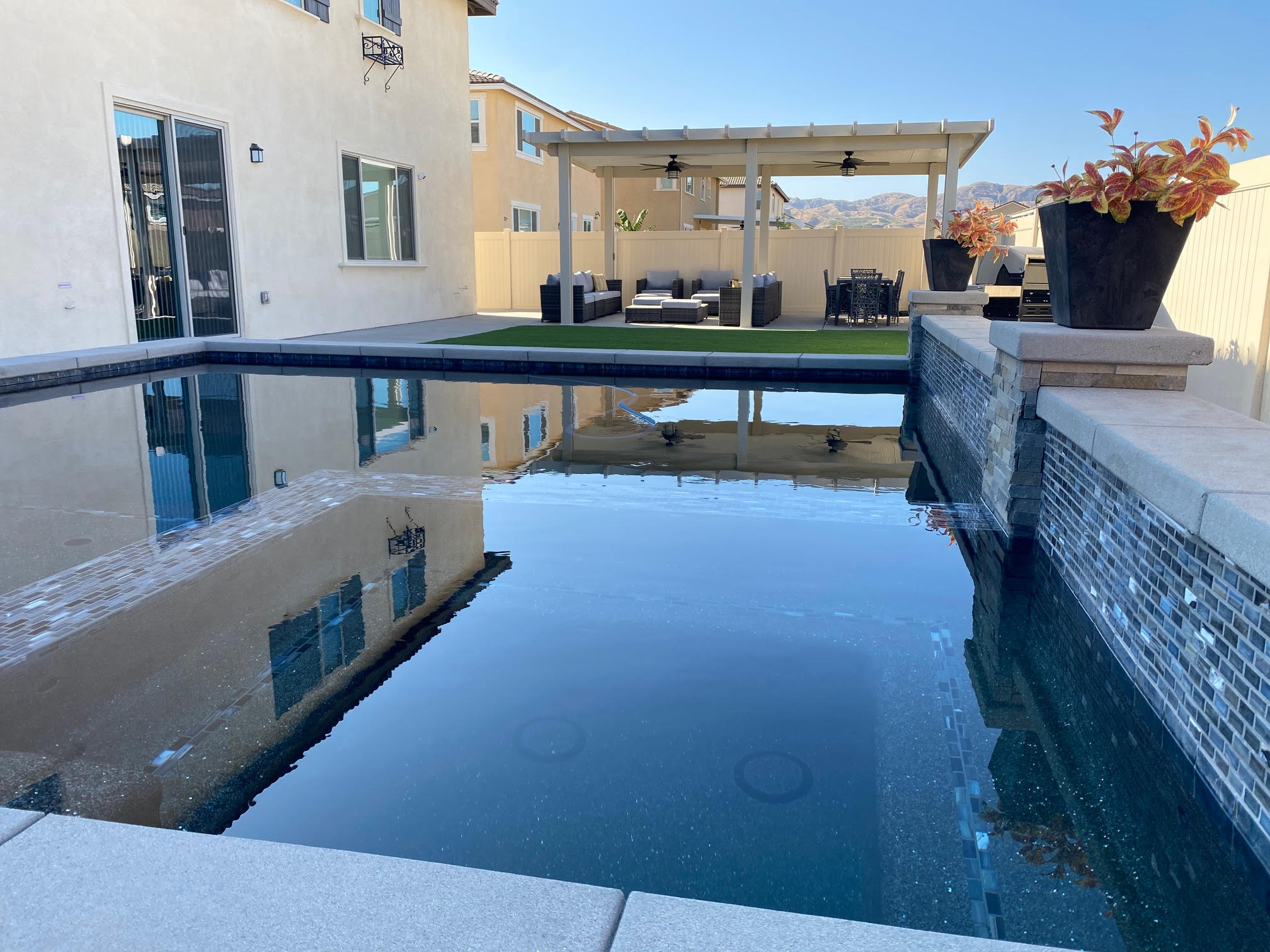 Modern black pergola structure against a clear blue sky — Elite Patios installation